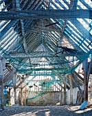 Net stretched beneath roof timbers in dilapidated barn