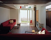 Rote Sofagarnitur im modernen Wohnraum und offenstehende Terrassentür