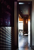 Würfelmotive auf Wand- und Bodenfliese im Vorraum und Blick durch offene Tür in Wohnraum