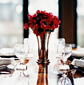 Red anemones in vase on set table