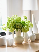 Viburnum in a White Vase with Assorted Vases on a Table