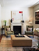 Upholstered armchairs and ottoman in front of fireplace in traditional setting
