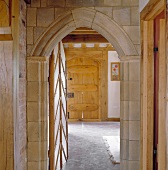Blick durch offene Tür mit gemauertem Spitzbogen in historischem Gebäude