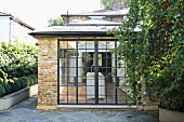 A single storey extension used as a kitchen with a brick facade and historic metal window frames