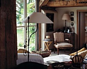 Antique collectors' items in small, cosy living room with exposed ceiling beams and terrace door leading to garden