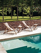 Deckchairs next to pool with masonry steps and lawn with trees