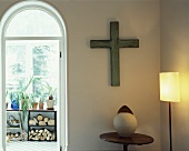 Cross on wall in corner of room and arched doorway leading to loggia
