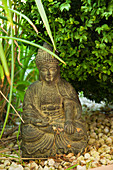 Asiatische Kunst - Kleine Buddhafigur aus Stein auf Kiesboden