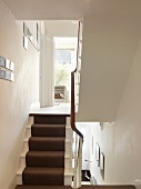 Dark stair runner on white-painted wooden stairs in traditional stairwell