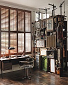 Vintage style desk below window with closed shutters next to shelves with collectors' items