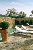 Swimming pool and sun loungers surrounded by stone wall