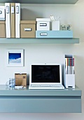 Well organized home office with a sideboard used as a work desk and wall shelving above; storage boxes on top of the shelves in assorted sizes