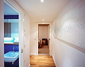 Modern hallway and open bathroom door with view of blue mosaic wall tiles