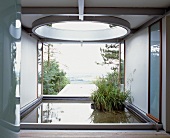 Loggia in zeitgenössischer Architektur mit Pflanzentöpfen im Wasserbassin vor Garten