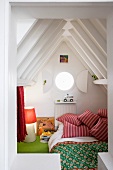 Cosy child's sleeping cabin with porthole under pointed, wooden attic roof