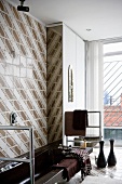 Dark brown bathtub and stainless steel towel rail against 70s, retro-style brown and white tiled wall
