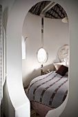 Keyhole-shaped doorway into lovingly decorated sleeping cabin with fabric canopy