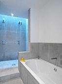 Grey-tiled, minimalist bathroom with open shower area lit from above