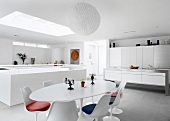 Modern designer kitchen and dining area with fifties retro furniture in open-plan white room