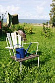 Old wooden chair with watering can in the garden with a view of the ocen
