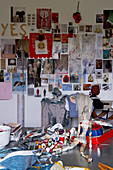 Nähutensilien und Stoffe auf Tisch vor Wand mit beklebten Postkarten