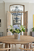 Bouquet on round wooden table in front of open, interior double doors