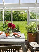 Rustikaler Holztisch im Glashaus mit Blick in Garten