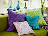 Cushions in a variety of colors on a green sofa