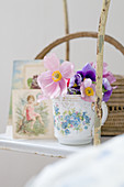 Romantic arrangement on vintage shelving - anemones in floral mug in front of nostalgic postcards