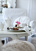 Vintage Tablett mit Frühstücksgeschirr und kleine Blumenvase mit Rosen auf antikem weisslackierten Tisch