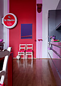 Objet d'art and beer advert in modern living-dining room against walls painted in vibrant pink and red