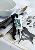 Cutlery decorated with small card and bird motif on paper next to place setting