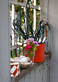 Rankhilfen, Blumen und Deko im Fenster des Gartenhauses