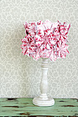 Red and white folded paper flowers on turned wooden stand
