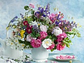 Bunter Blumenstrauss in weisser Vase neben Teekanne