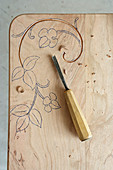 Carving a wooden board with a floral design