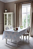 Rococo chairs and white tablecloth with linocut print in rustic dining area