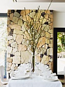 Festlich gedeckter Tisch vor dekorativer Natursteinmauer im Speisezimmer