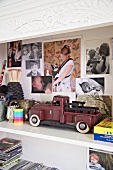 Vintage Spielzeugauto auf Regal und Familienphotos an Rückwand des Regalschrankes