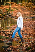 Woman crossing a stream in autumnal forest