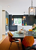 Kitchen-dining room: stained wood dining table, marble kitchen island and transparent lanterns