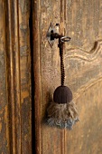 Key chain with feathers hanging from the old, battered door of country home