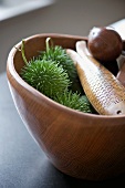Horse chestnuts in green prickly shells and wooden fish in handcrafted wooden bowl