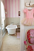 Bathroom with freestanding bath tub and pink and white striped wallpaper