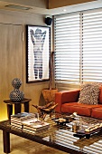 Wohnzimmerecke mit afrikanischen Kunstobjekten auf Holzhocker und Couchtisch vor moderner Ledercouch