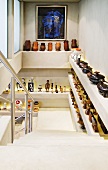 A collection of ceramic containers and figures on built-in shelves in a stairwell