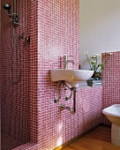 White sink on wall with claret mosaic tiles and open shower area in designer bathroom