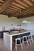 Contemporary kitchen counter with designer bar stools in open-plan kitchen of renovated country house