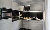 Moderne Einbauküche mit grauen Schrankfronten & schwarzen Arbeitsplatten und Rückwänden