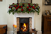 English Christmas decoration: sumptuous garland of roses on mantelpiece above roaring fire